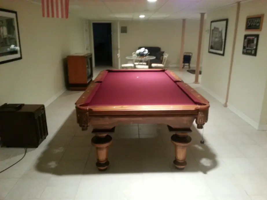 A burgundy felt table with turned legs in a finished basement
