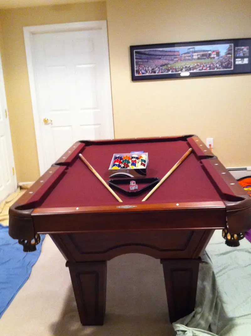 Burgundy felt on a table corner with two cues crossed and a set of balls