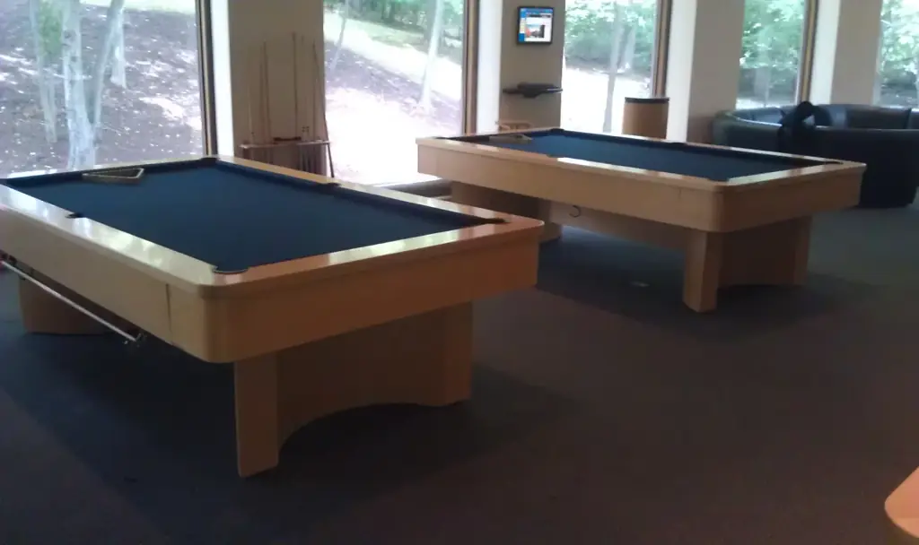 Two light oak tables with navy felt in a room of tall windows