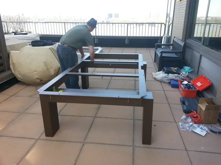 A pool table frame being assembled on a tiled terrace before the slate goes on
